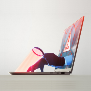 Imagen de manos sosteniendo una lupa que se extiende a través de la pantalla de una computadora para mirar el teclado.