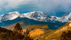 Imagen de las Montañas Rocosas de Colorado en otoño. En primer plano hay valles de pinos y hierba otoñal.