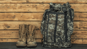 Un par de botas de estilo militar junto a una mochila de camuflaje.